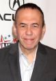 Gilbert Gottfried smiling at an event, showcasing his signature humor and charisma against a branded backdrop.