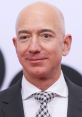 Jeff Bezos smiling in a suit and patterned tie at a public event, showcasing his influential presence in business and technology.