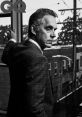 Jordan Peterson poses thoughtfully by a rain-streaked window, embodying a contemplative mood in a stylish suit.