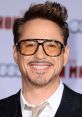 Robert Downey Jr. smiling in stylish glasses at a premiere event, showcasing his charismatic personality and fashion sense.