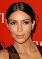 Kim Kardashian showcasing a flawless makeup look and sleek hairstyle, captured at a glamorous event with a vibrant backdrop.