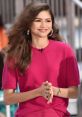 Zendaya smiles while wearing a vibrant pink outfit, showcasing her iconic style and charm at a public appearance.