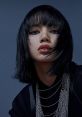 Lisa flaunts an edgy look with sleek black hair, bold makeup, and layered silver chains, exuding confidence and style.