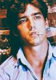 Vincent Terranova with a cigarette, showcasing a contemplative expression against a brick background.