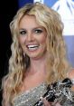 Britney Spears shines during an award ceremony, holding a trophy and beaming with joy, showcasing her iconic look.