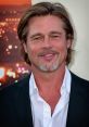 Brad Pitt smiles confidently, showcasing his signature style with tousled hair and a sleek outfit at a red carpet event.