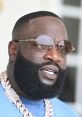 Rick Ross sporting stylish sunglasses and a bold beard, showcasing his signature look with intricate tattoos and chains.