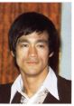 Bruce Lee with a confident expression, showcasing his iconic hairstyle and style, representing martial arts legacy.