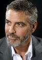 Close-up portrait of George Clooney, showcasing his distinguished gray beard and stylish suit against a dark background.