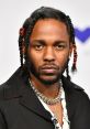 Kendrick Lamar showcasing distinct style with braided hair and layered necklaces at a public appearance.