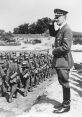 Hitler salutes soldiers during a military review, showcasing Nazi uniforms and the era's military discipline.