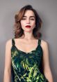 Emilia Clarke exudes elegance in a vibrant tropical print dress, showcasing her stunning features and bold red lips.