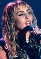 Miley Cyrus performing passionately on stage, wearing a stylish outfit and holding a microphone, showcasing her vocal talent.