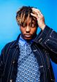 Juice WRLD poses thoughtfully against a vibrant blue background, showcasing his unique style and expressive personality.