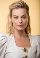 Margot Robbie with shoulder-length blonde hair, wearing a stylish white dress, photographed against a yellow background.