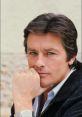 Close-up of a handsome man with dark hair and blue eyes, thoughtful expression, wearing a casual outfit and wristwatch.