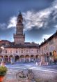 Historic Piazza with a striking clock tower, cobblestone paths, and quaint bicycle in a charming Italian town.