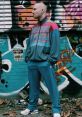 Young man in vintage tracksuit poses confidently against vibrant graffiti backdrop, embodying Gabber culture and style.