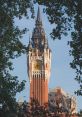 Historic bell tower with intricate architecture framed by lush greenery against a clear blue sky.