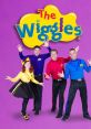 The Wiggles perform joyfully in colorful outfits against a vibrant purple background, promoting fun and music for kids.