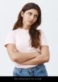 Woman with a displeased expression, arms crossed, conveying annoyance in a casual outfit against a simple background.