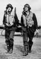 Two RAF pilots in vintage flight gear walking confidently on an airfield, showcasing aviation history and camaraderie.