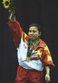 Gold medalist proudly celebrates victory, holding sunflowers in a vibrant red and yellow champion’s outfit.