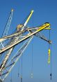 Cranes at port lifting equipment against a clear blue sky, showcasing industrial machinery and maritime logistics.