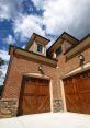 Elegant wooden garage doors complement brick exterior and upscale architecture, enhancing curb appeal and home aesthetics.