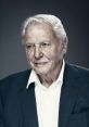 David Attenborough, renowned naturalist, smiles warmly in a formal suit, embodying wisdom and passion for wildlife conservation.