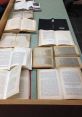 Scattered open books on a table in a library, showcasing worn pages and diverse texts. Perfect for a rainstorm reading session.