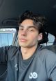 Young German male with stylish hair, wearing a black athletic shirt, posing in a car. Casual and confident demeanor.