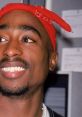 Tupac Shakur smiling with a red bandana, showcasing his iconic style and charisma in hip-hop culture.