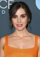 Alison Brie shines in a vibrant orange dress, showcasing her beauty at a recent event with striking blue eyes and radiant smile.