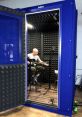 Man playing guitar in a portable vocal booth, showcasing optimal sound quality for recording in-house vocal libraries.