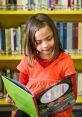 Young student in an orange shirt engrossed in a colorful book at a vibrant library filled with books.