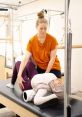 Pilates instructor assists a student with stretching techniques on a reformer, promoting flexibility and wellness.