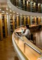 Student studying in a modern library, focused on a laptop, surrounded by shelves filled with books.