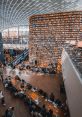 Modern library in a shopping center, featuring wooden bookshelves and study areas filled with people engaging in reading.