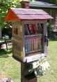 Little Free Library on a tree, filled with colorful books, promoting community reading at Edge Of Town Library.