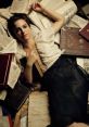 Young woman lying among scattered books, embodying a seductive literary allure in a stylish library setting.