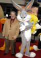 Joe Alaskey poses with Bugs Bunny and other Looney Tunes characters at a red carpet event, celebrating animated classics.