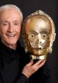 Anthony Daniels holds a C-3PO mask, showcasing his iconic role as the beloved droid in the Star Wars franchise.