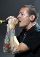 Chester Bennington passionately performing on stage, showcasing his iconic tattoos and powerful vocal expression.