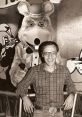 John Widelock poses with Chuck E. Cheese mascot, celebrating the family entertainment legacy from 1977 to 1983.