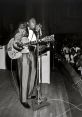 Dynamic rhythm and blues performance with a guitarist singing into a vintage microphone on stage, captivating the audience.