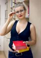 Confident woman in a library holding colorful books, perfect for a hot day of summer reading and studying indoors.