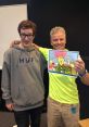 Fans pose with Matt Hill, voice actor of Ed from Ed Edd n Eddy, holding a signed cartoon art piece.