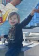 Smiling child in a black shirt reaches out joyfully, with colorful mural and modern setting in the background.