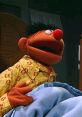 Ernie in pajamas, looking surprised while sitting in bed, capturing his playful personality from Sesame Street.